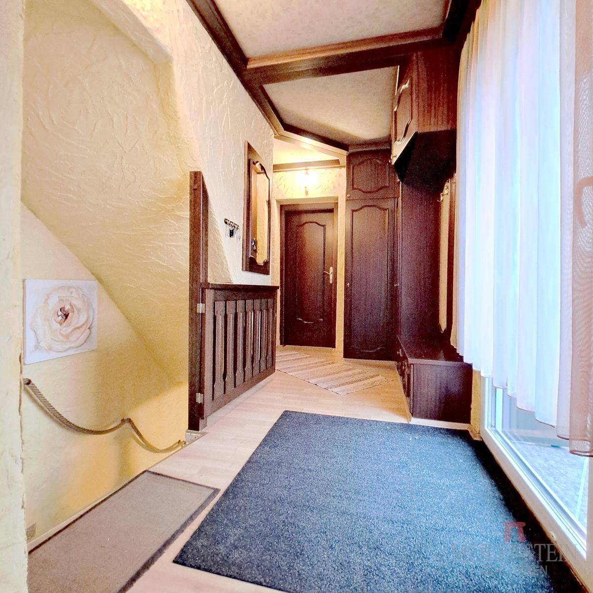 Geräumiger Flur mit Holzverkleidung, Laminatboden, Einbauschränken und großem Fenster.