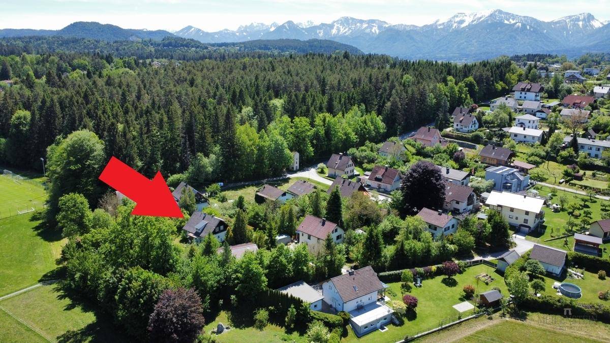 Weitläufige Luftaufnahme einer ländlichen Wohnsiedlung mit bewaldeter Umgebung und Bergen.