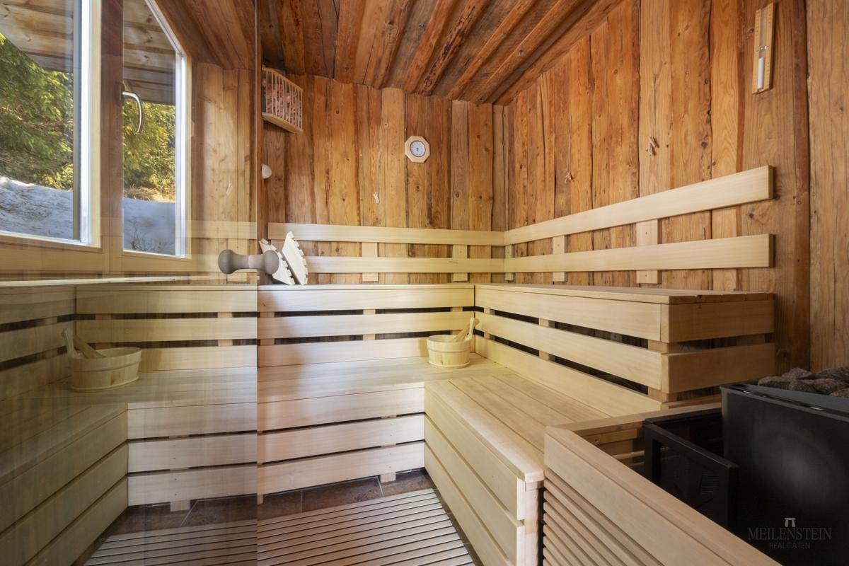 Geräumige Holzsauna mit mehreren Bänken und großem Fenster.