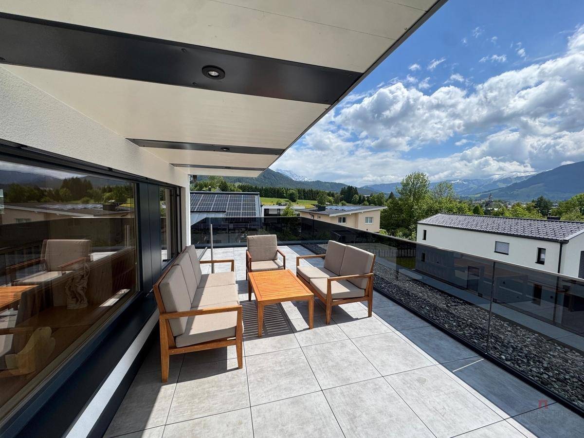 Geräumiger Balkon mit modernen Gartenmöbeln und weitem Blick auf die umliegende Landschaft.
