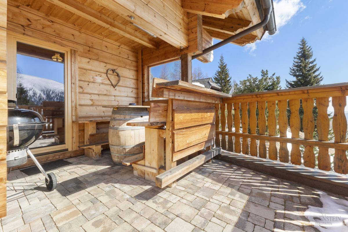Sonniger Balkon mit Grill, Holztisch und Bergblick.