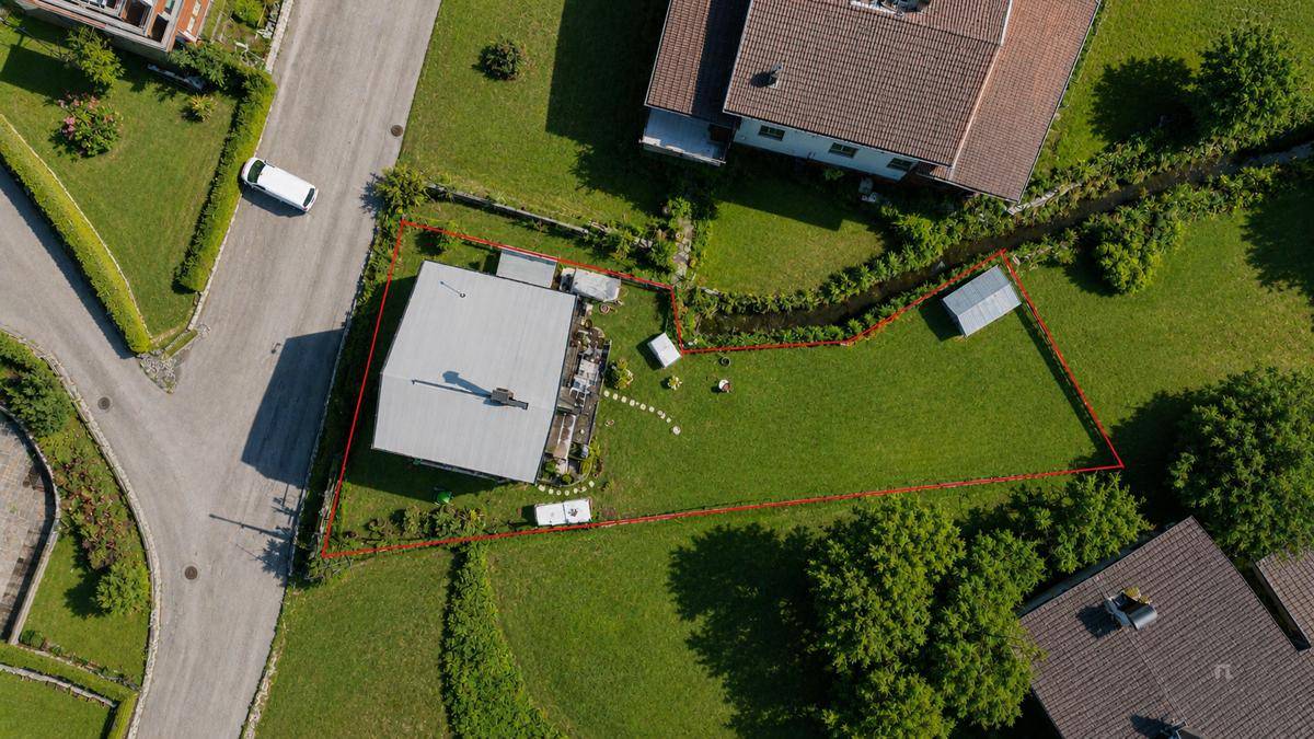 Luftaufnahme eines Einfamilienhauses mit großem Garten, Rasenfläche und angrenzender Straße in ländlicher Umgebung.