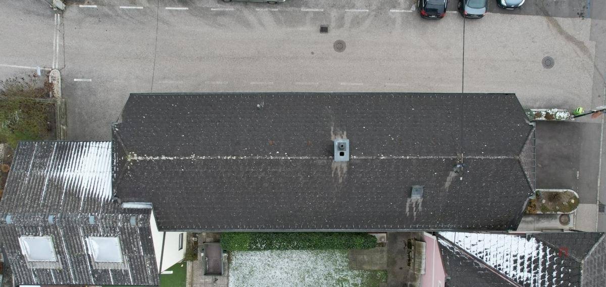 Dachansicht des Gebäudes mit Satteldach und umliegenden Dächern und Straßen.