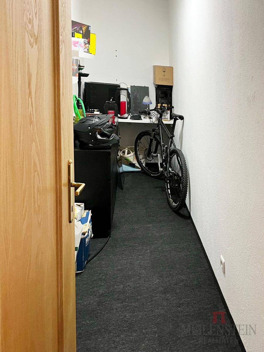 Kleiner Mehrzweckraum mit Schreibtisch, Fahrrad und Teppichboden.