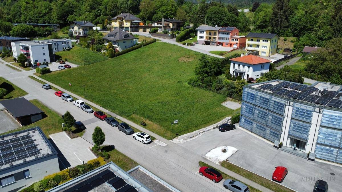 Luftaufnahme eines großen grünen Grundstücks, umgeben von Wohnhäusern und einigen Geschäftsgebäuden in einer ländlichen Umgebung.