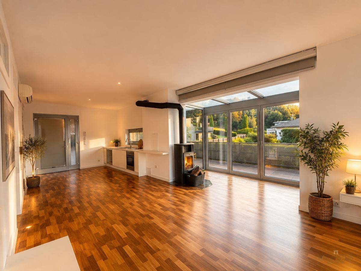 Offener Wohn- und Essbereich mit Holzboden, Kaminofen und Zugang zu einer verglasten Terrasse.