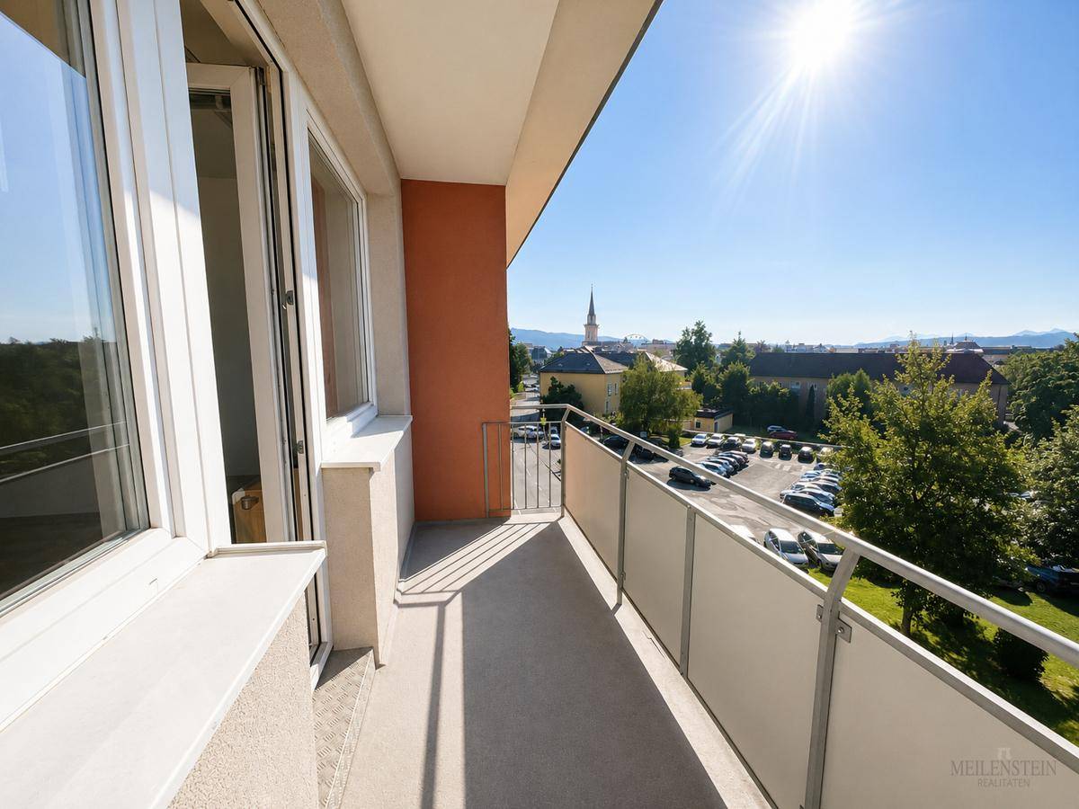Heller Balkon mit Metallgeländer und weitem Blick über die Stadt und die umliegende Landschaft.