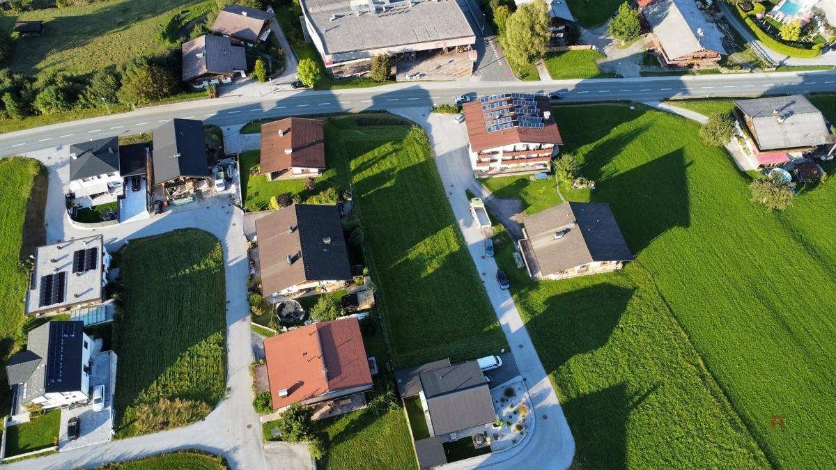 Weitläufige Luftaufnahme einer Siedlung, eingebettet in grüne Wiesen und mit Blick auf die Umgebung.