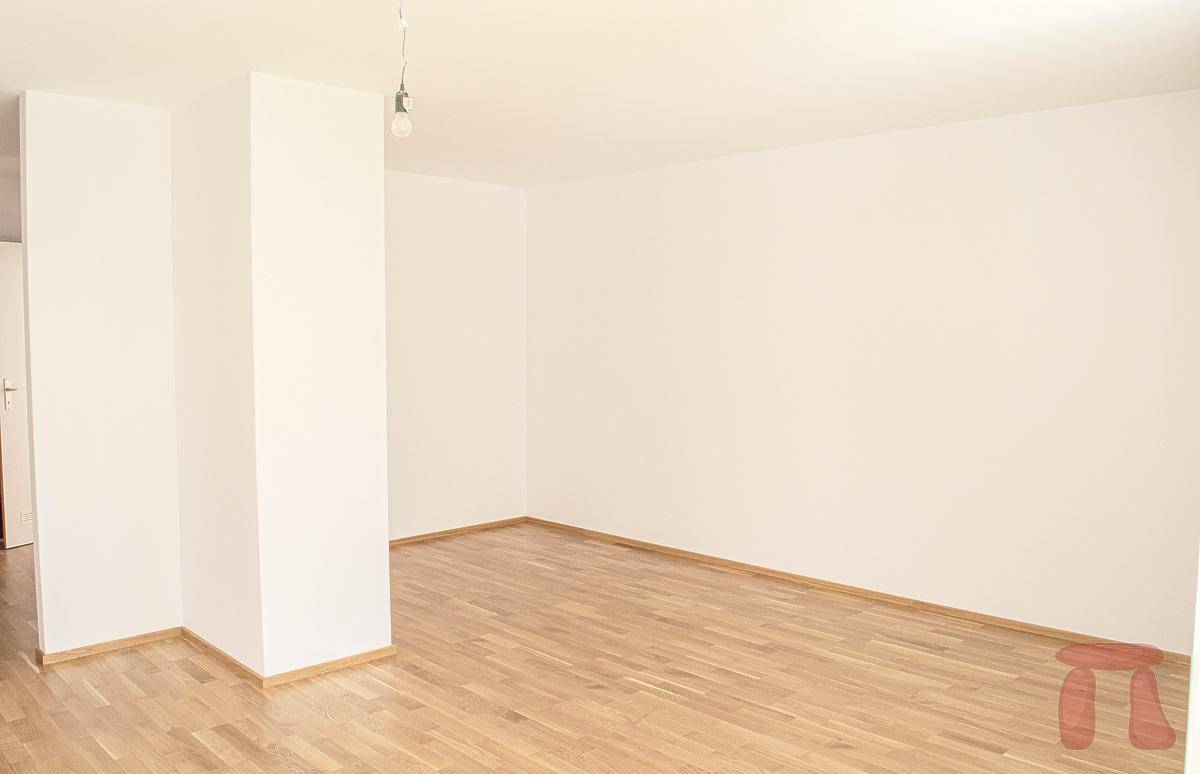 Geräumiges, leeres Zimmer mit hellem Parkettboden und weißen Wänden, ideal für individuelle Einrichtung.