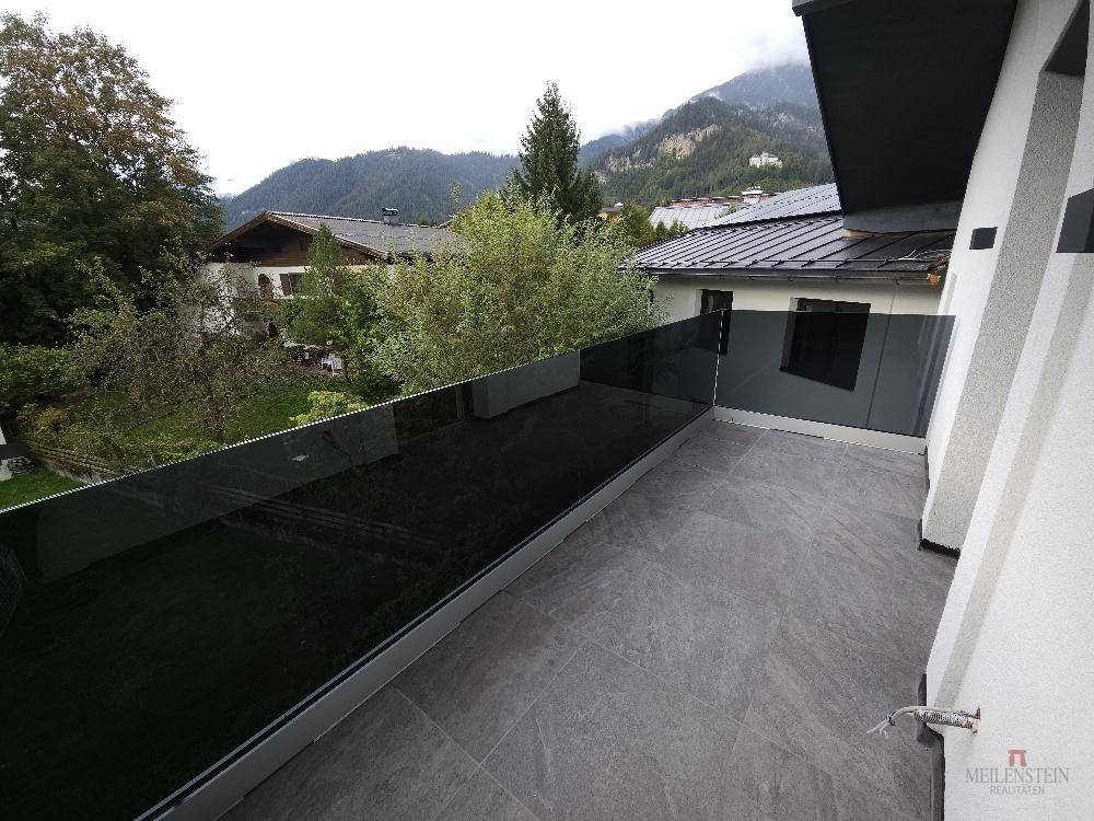 Balkon mit moderner Glasbrüstung und weitem Blick auf die grüne Berglandschaft.