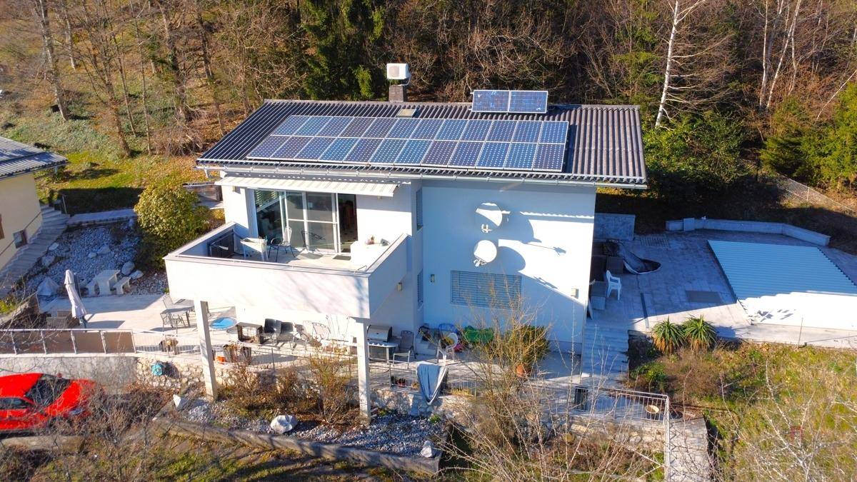 Luftaufnahme eines modernen Hauses mit Solaranlage auf dem Dach und weitläufiger Außenanlage.