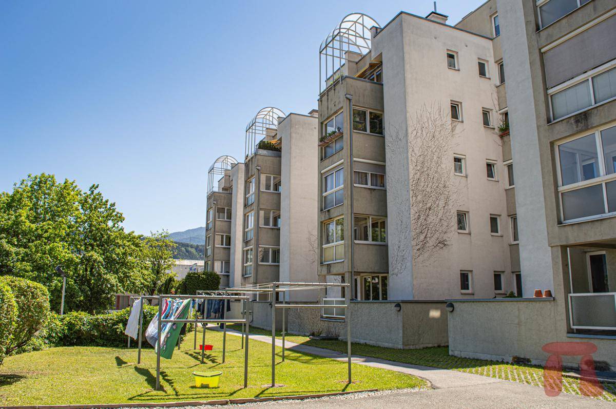 Seitenansicht des Wohnhauses mit Wäscheleinen im Gartenbereich und grüner Umgebung unter blauem Himmel.