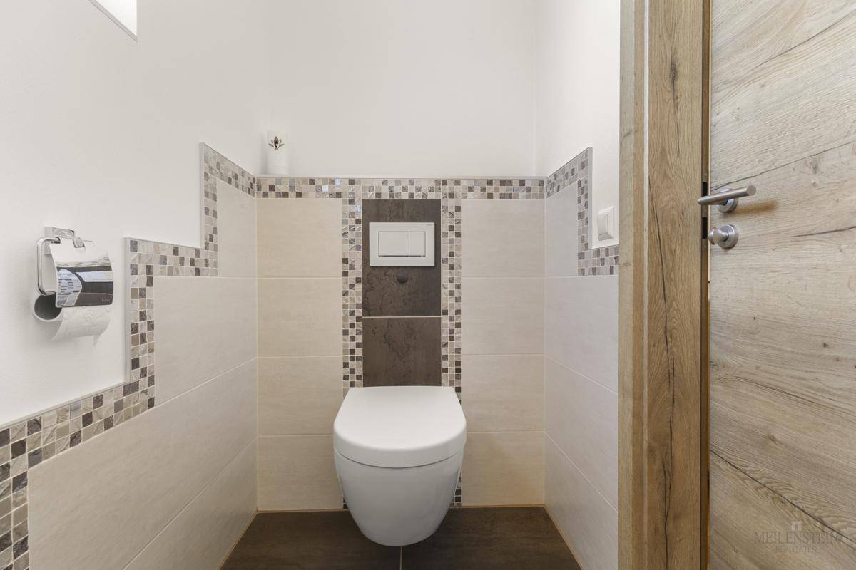 Modern gefliestes Gäste-WC mit Wand-WC und dekorativen Mosaikfliesen.