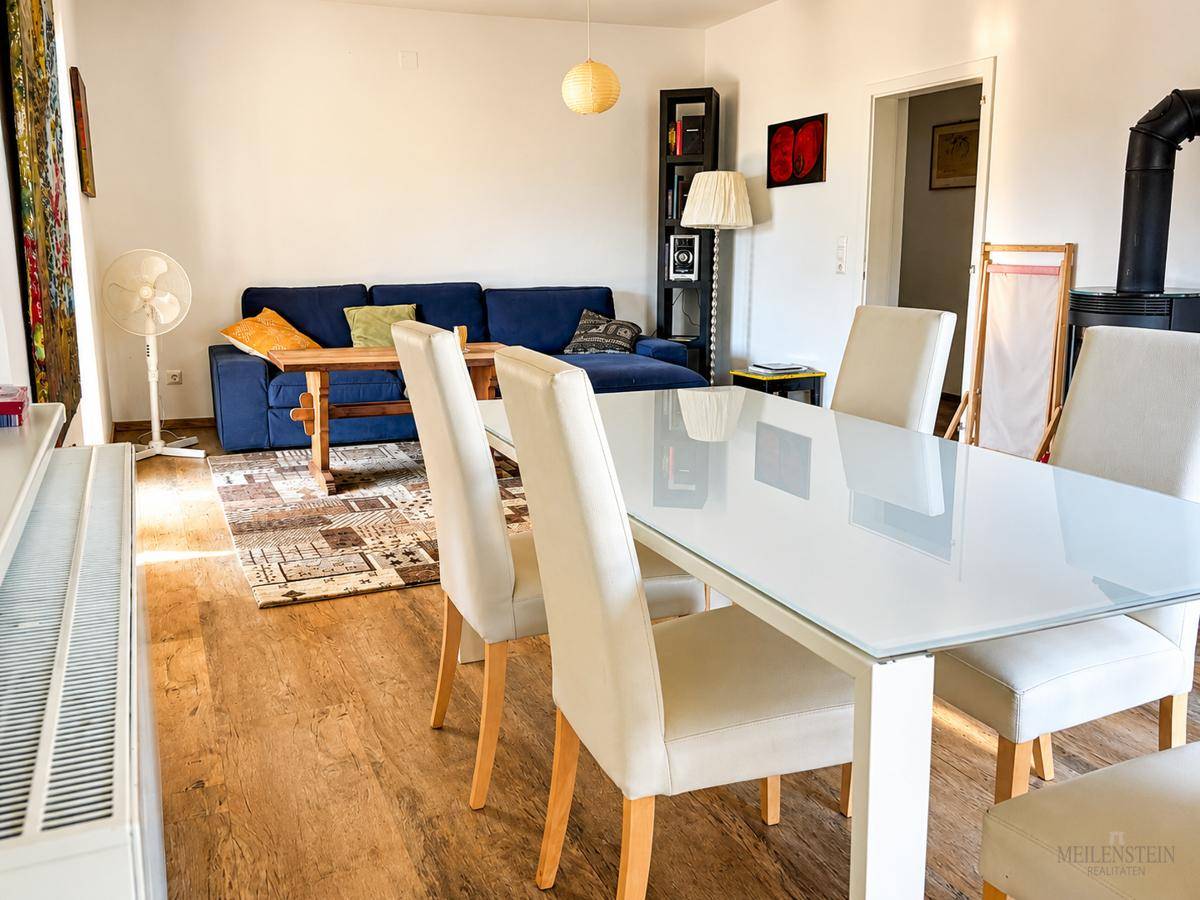 Gemütlicher Wohn-Essbereich mit Esstisch, blauem Sofa und einem Holzofen für zusätzliche Wärme.