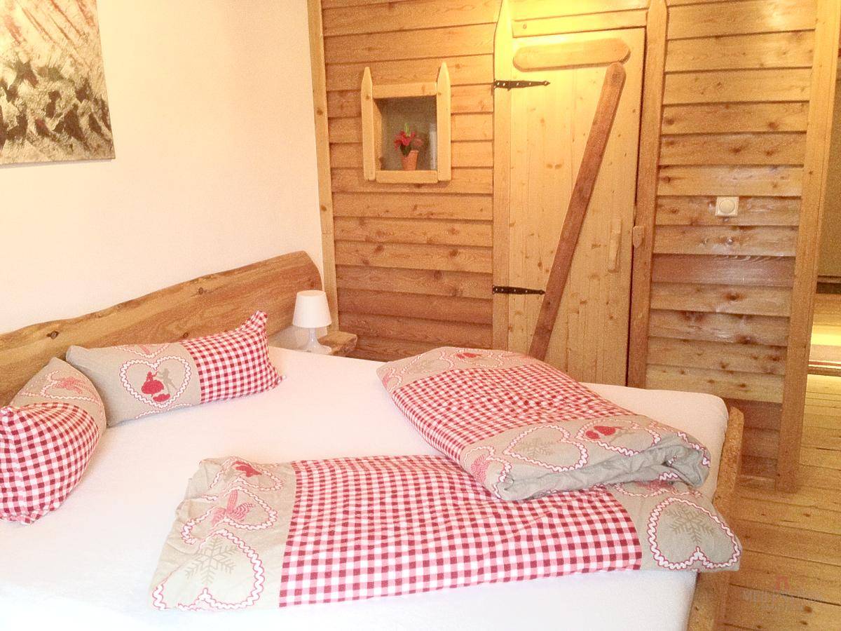 Gemütliches Schlafzimmer im alpinen Stil mit Holzwänden und karierter Bettwäsche.