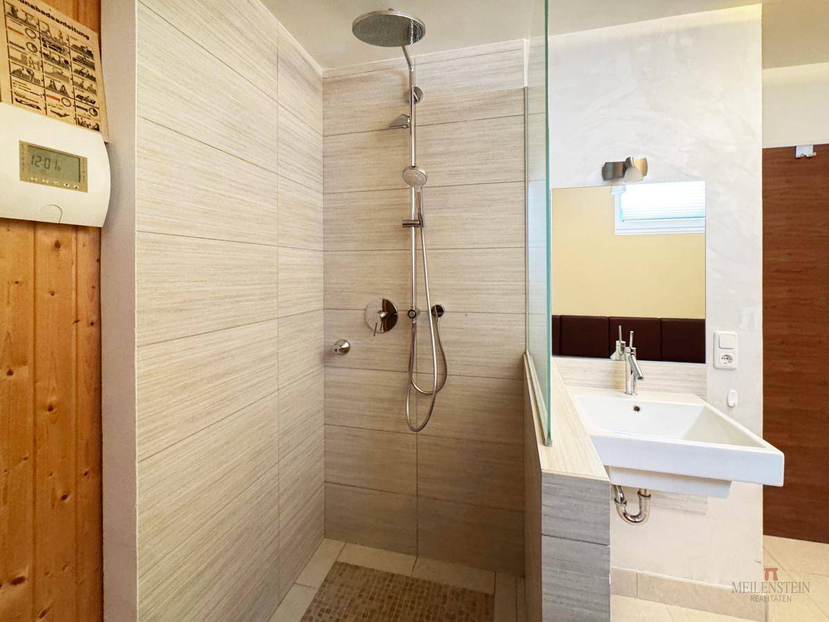 Helles Badezimmer mit begehbarer Dusche und modernem Waschbecken, minimalistisch gestaltet.