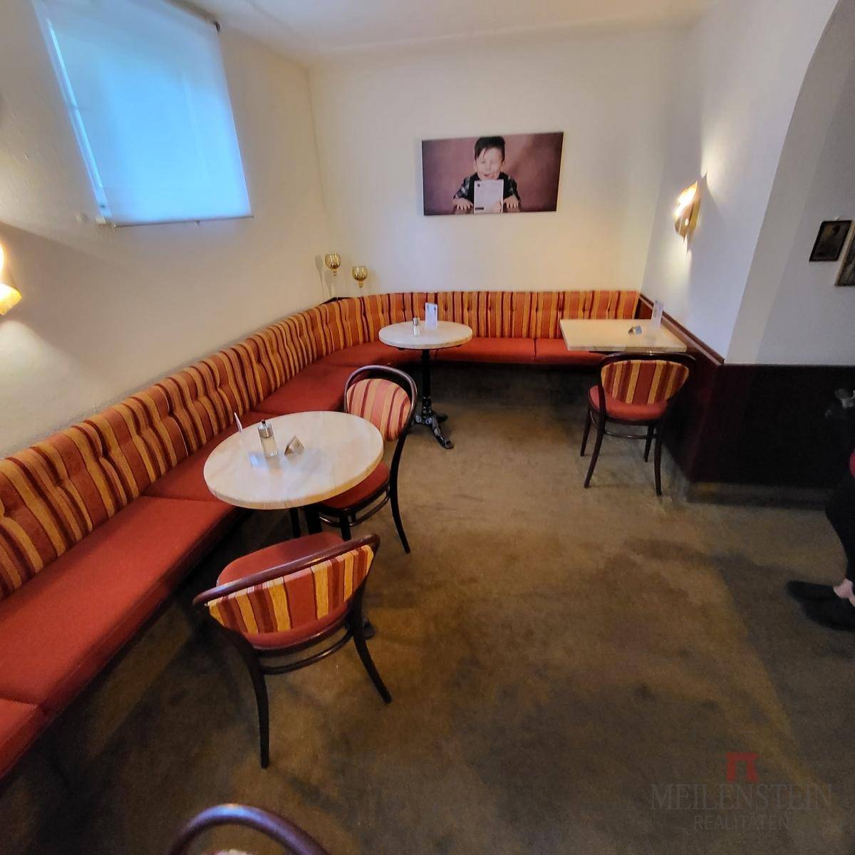 Weiterer Blick auf den gemütlichen Eckbereich des Cafés mit gepolsterten Sitzgelegenheiten und kleinen Tischen.