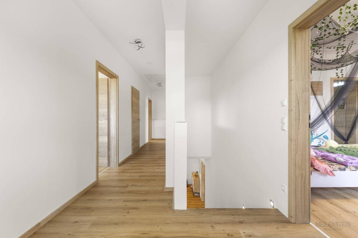 Heller Flur im Obergeschoss mit Holzboden und Zugang zu mehreren Zimmern.