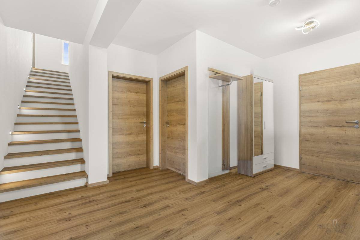 Heller Eingangsbereich mit Holztreppe, modernen Holztüren und Garderobe.