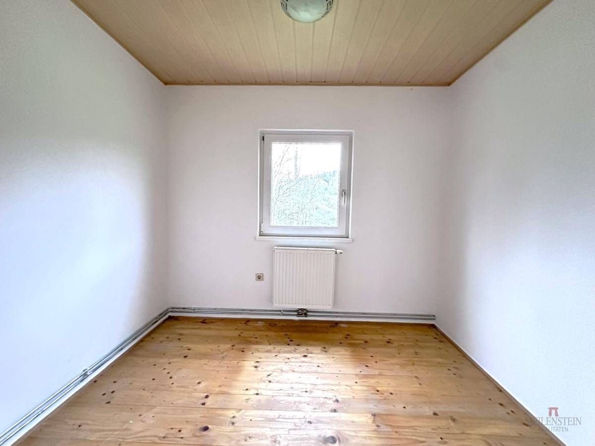 Kleiner Raum mit Holzboden und einem Fenster, das viel Tageslicht hereinlässt.