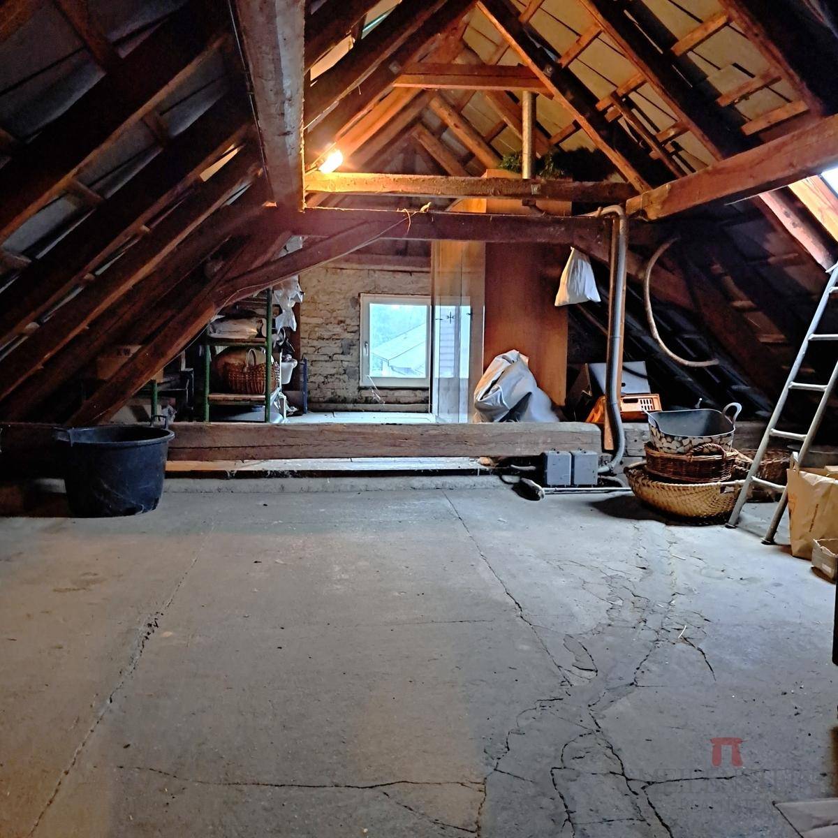 Geräumiger Dachboden mit sichtbaren Holzbalken, Betonboden und viel Stauraum.