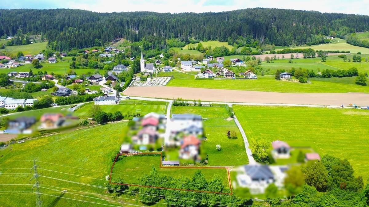 Luftaufnahme eines ländlichen Grundstücks mit Blick auf ein Dorf, Wälder und Berge.