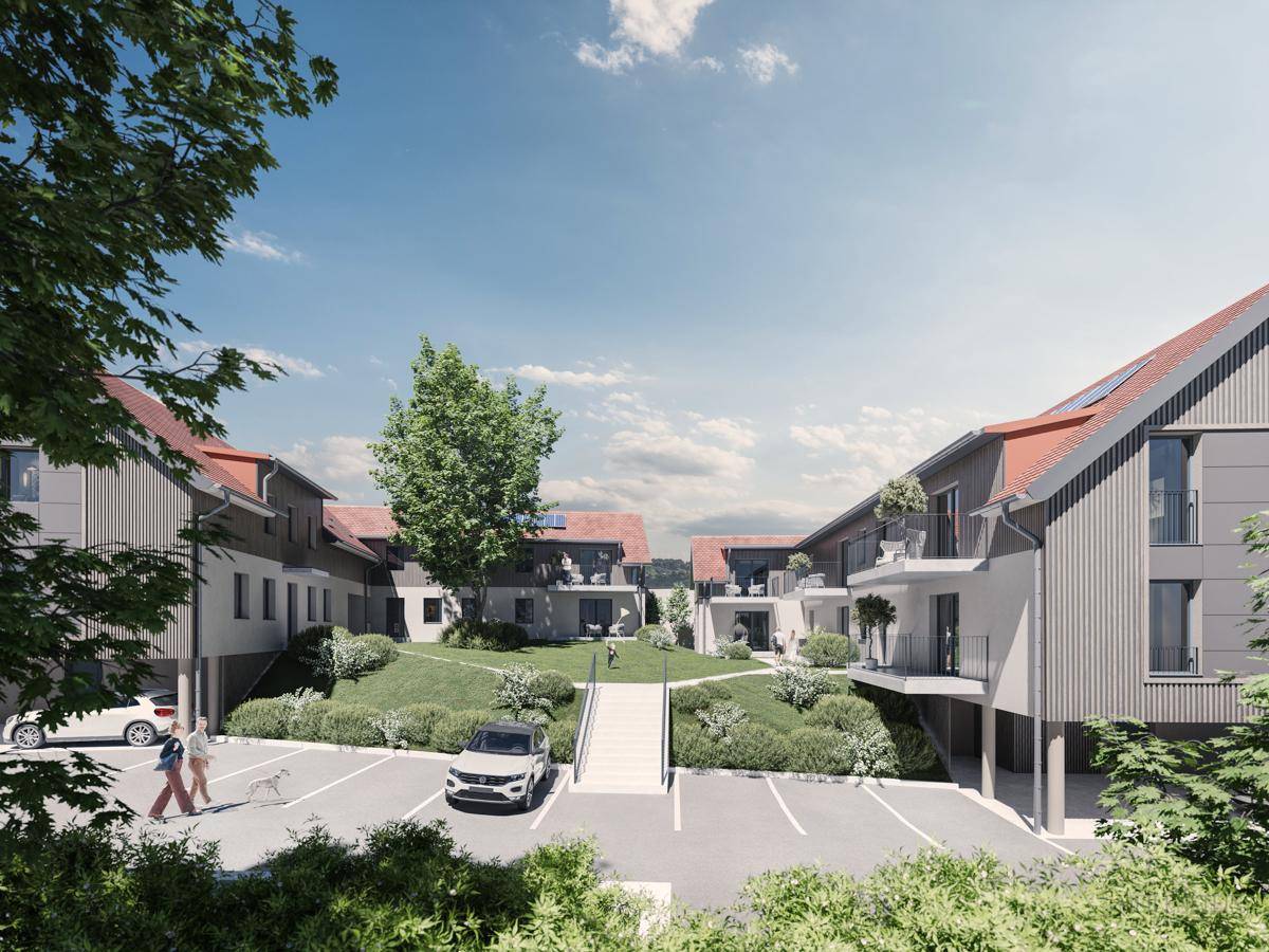 Ansicht der Wohnanlage vom Parkplatz aus, umgeben von Grünflächen und modernen Gebäuden.