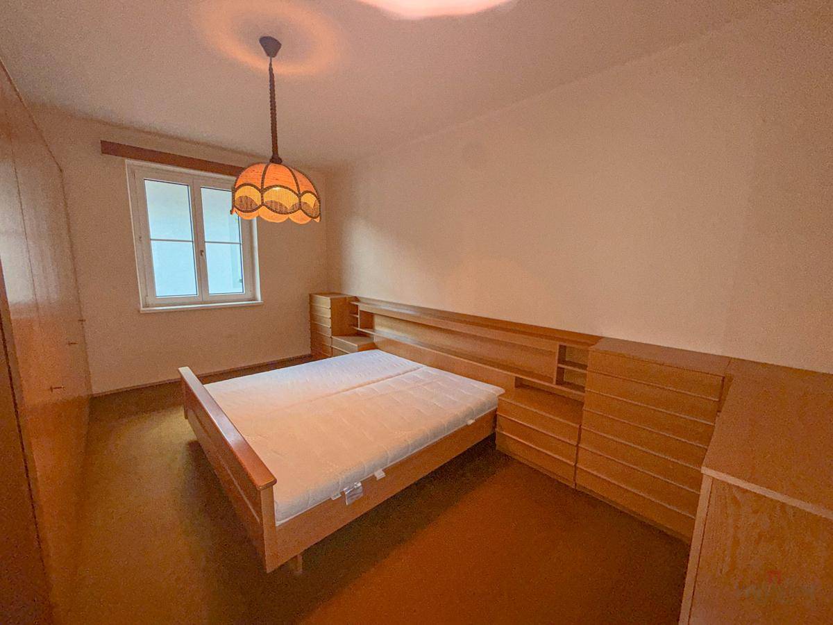 Gemütliches Schlafzimmer mit Holzbett, Einbauschränken und einem Fenster.