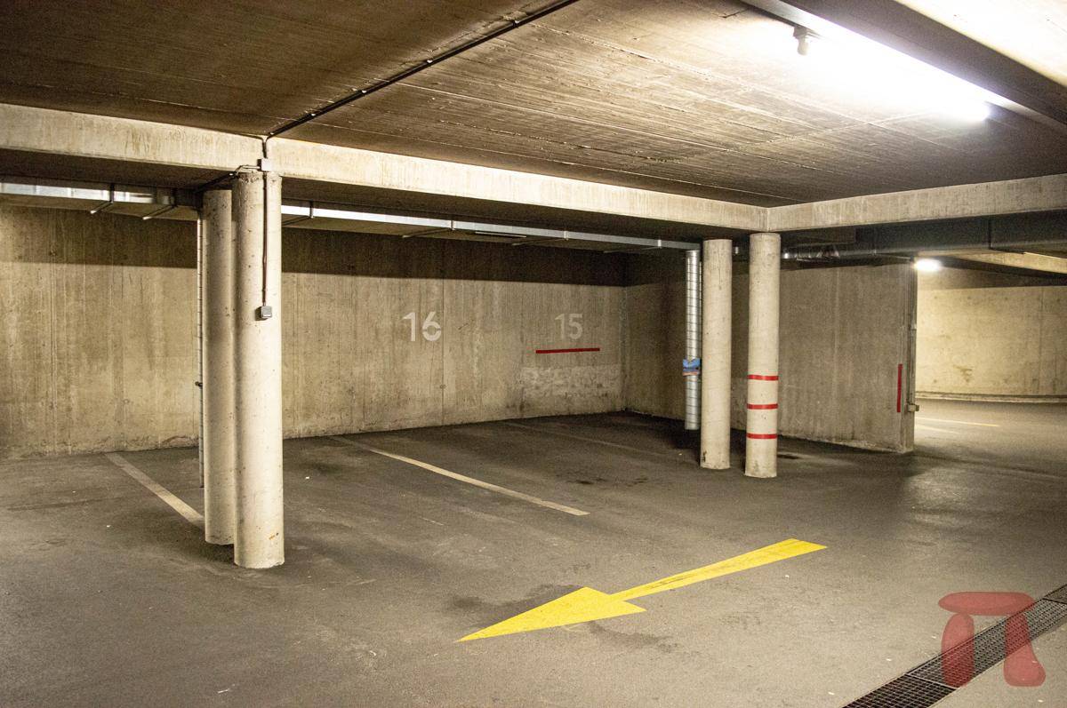 Geräumige Tiefgarage mit markierten Parkplätzen und Betonstützen im Untergeschoss des Gebäudes.