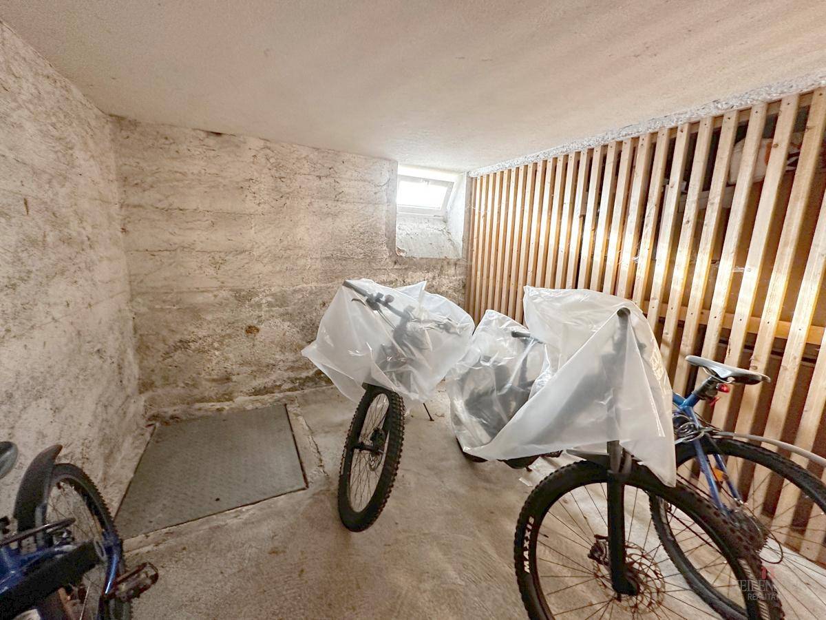 Kellerraum mit Fahrrädern und einer Holzlattenverkleidung, ideal als Abstellfläche.