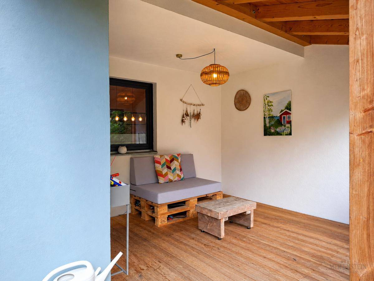 Überdachter Außenbereich mit Palettenmöbeln und Holzboden, ideal zum Entspannen im Freien.