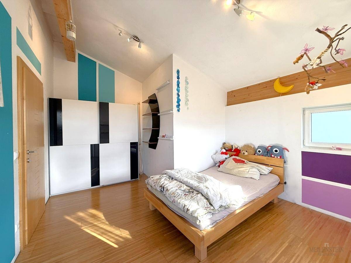 Kinderzimmer mit Holzboden, farbigen Wänden und einem Bett, hell und freundlich gestaltet.