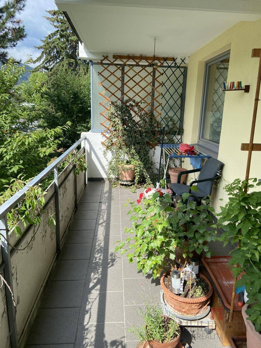 Gemütlicher Balkon mit Pflanzen und Blick ins Grüne, ausgestattet mit einem kleinen Tisch und Stuhl.