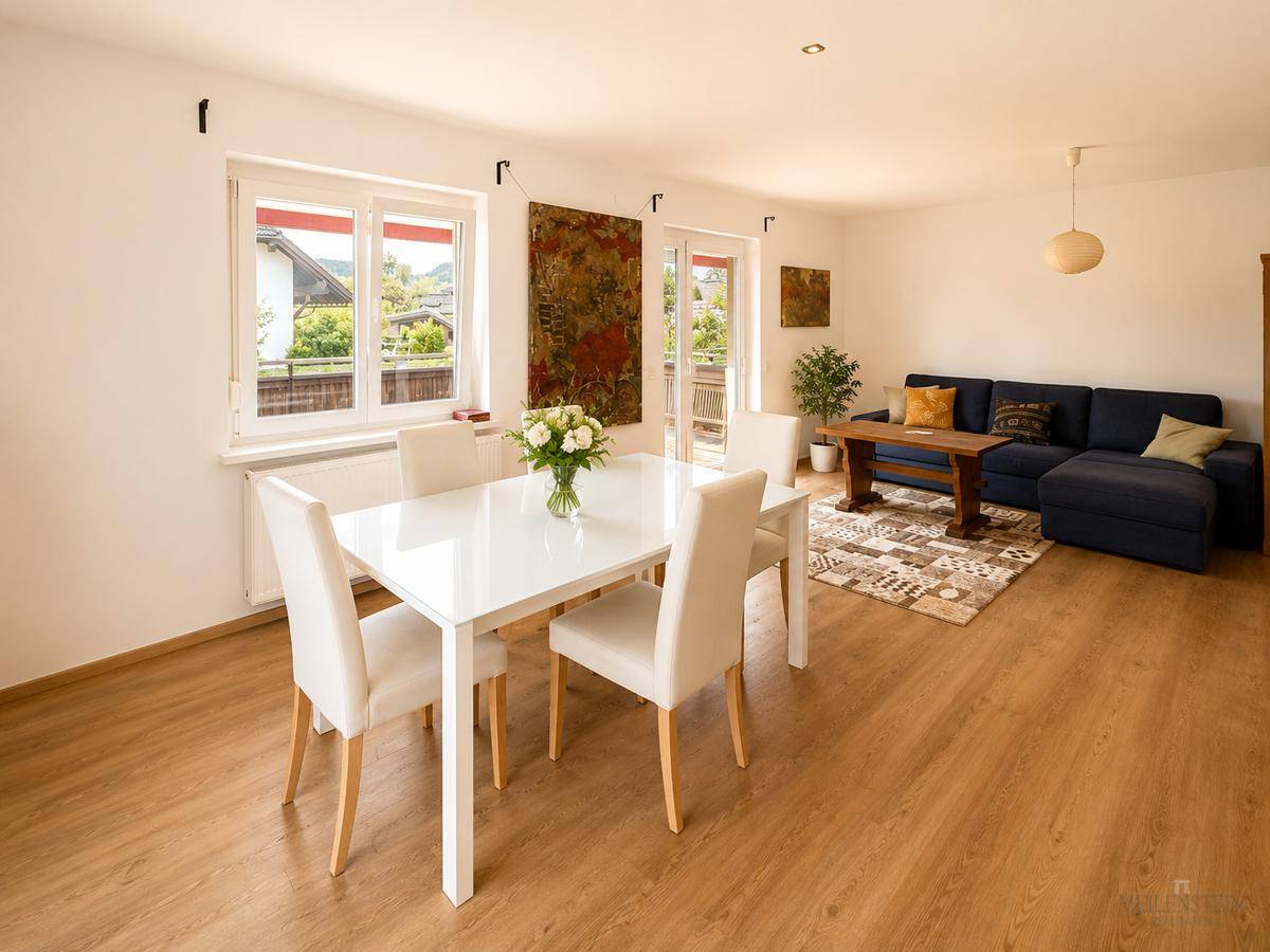 Heller Wohn- und Essbereich mit modernem Esstisch, Sofa und Zugang zum Balkon.