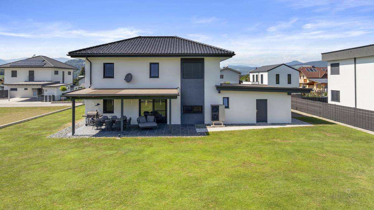 Rückansicht des modernen Hauses mit großem Garten und Blick auf die umliegende Landschaft.