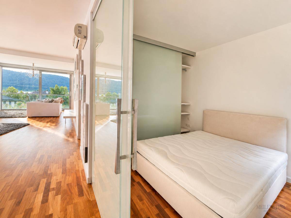 Schlafzimmer mit Holzboden und Schiebetür zum Wohnbereich, bietet einen Blick auf den See.