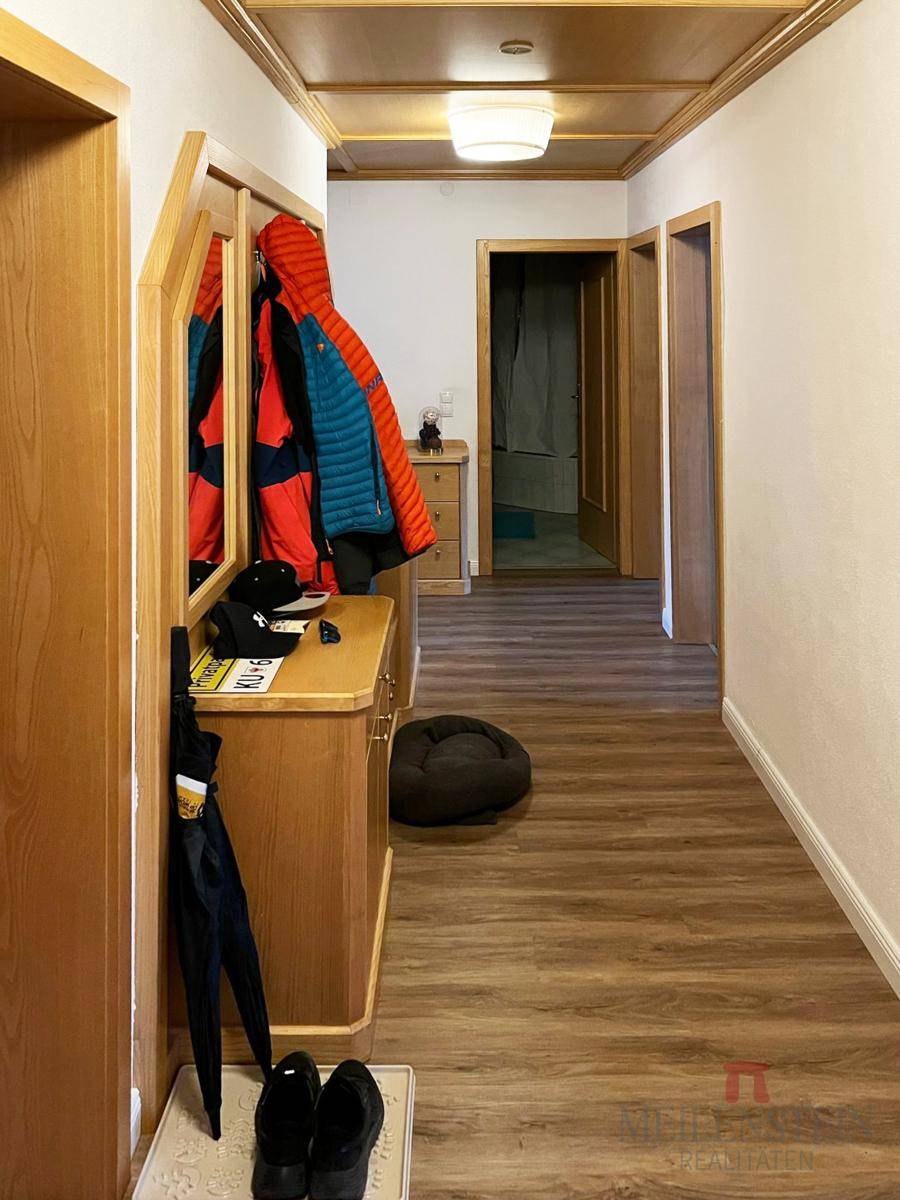 Heller Flur mit Holzdecke, Garderobe und Laminatboden, der zu weiteren Räumen führt.