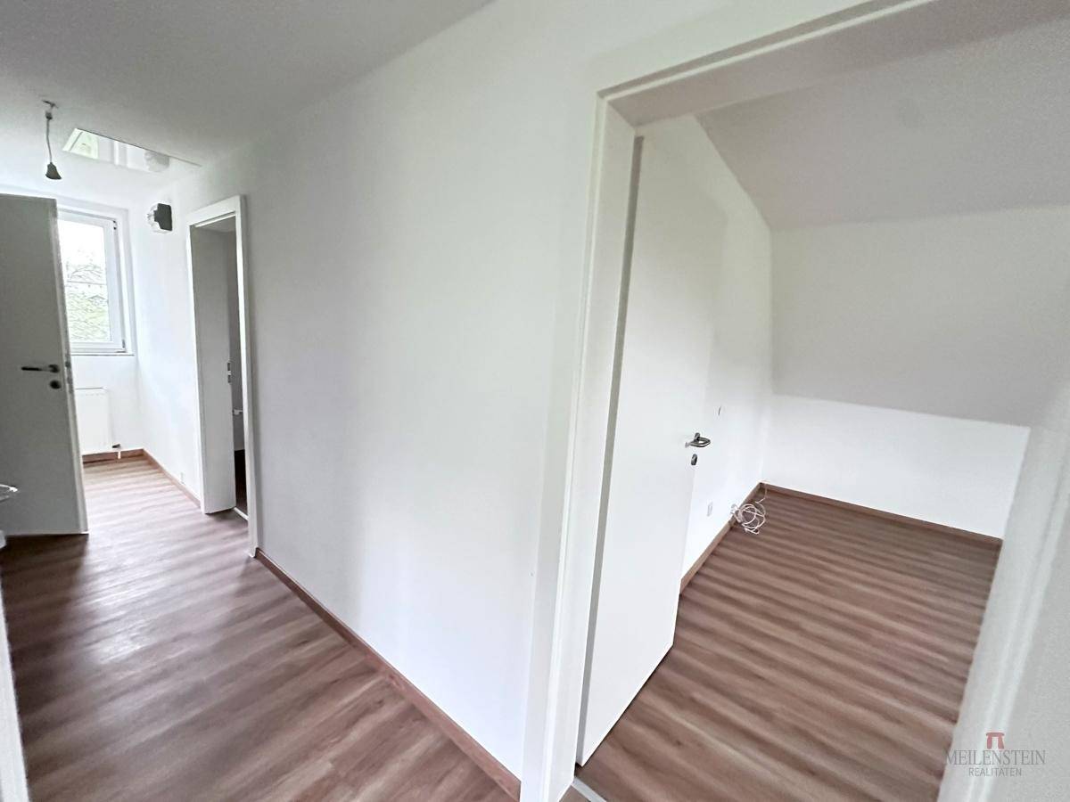 Heller Flur mit Laminatboden, der zu verschiedenen Zimmern im Obergeschoss führt.