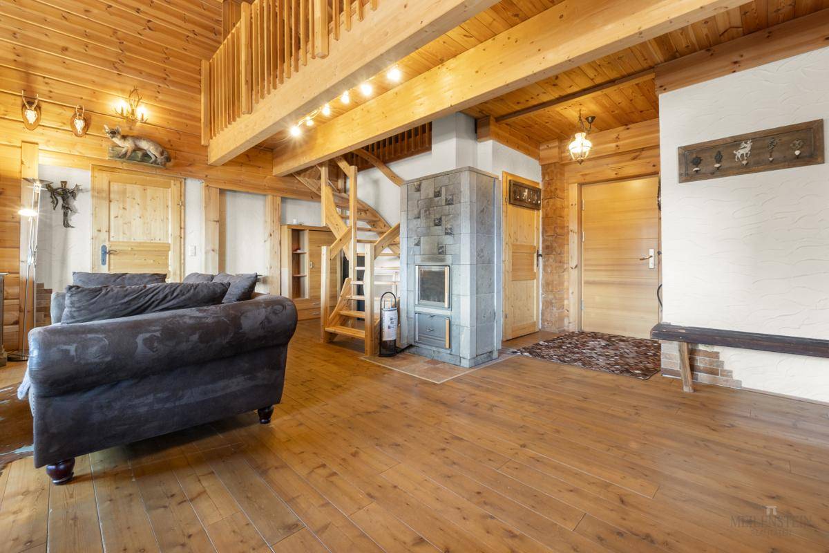 Wohnzimmer mit traditionellem Kachelofen, Holztreppe und rustikaler Einrichtung.