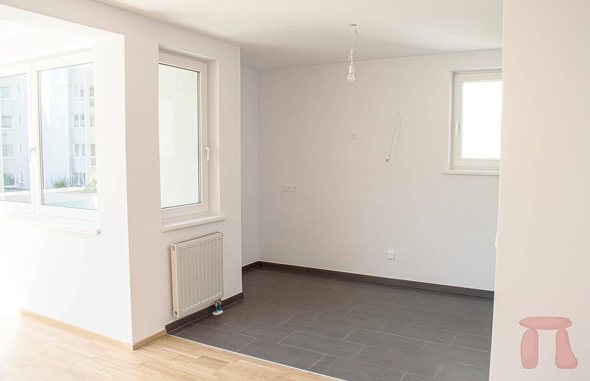 Leerer Raum mit dunklen Fliesen und einem Fenster, bereit für die individuelle Gestaltung.