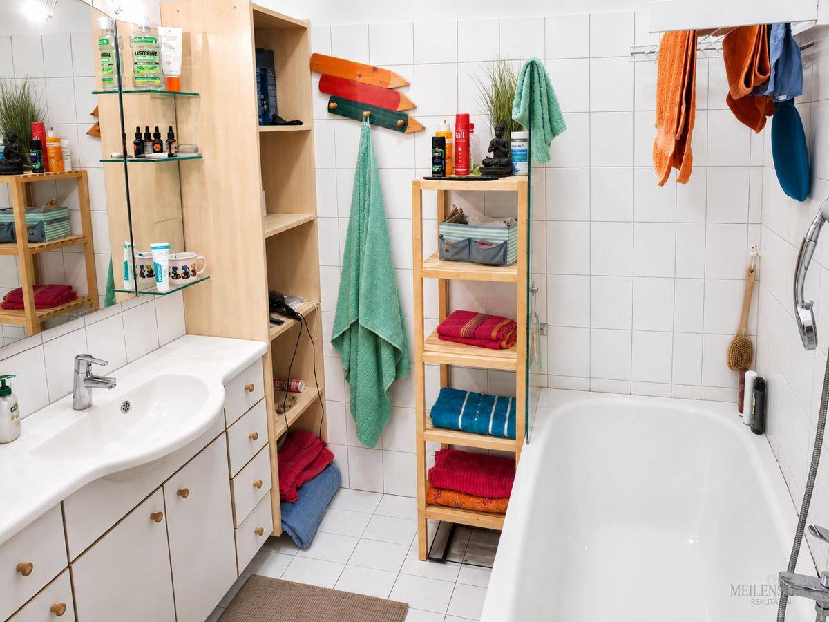 Funktionales Badezimmer mit Badewanne, Einzelwaschbecken und weißen Fliesen an den Wänden.