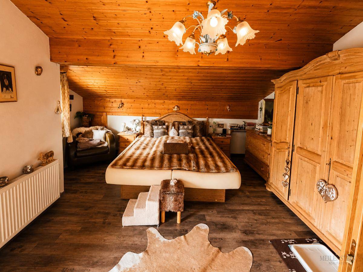 Geräumiges Schlafzimmer im Dachgeschoss mit Holzdecke, Holzboden und traditionellen Möbeln.