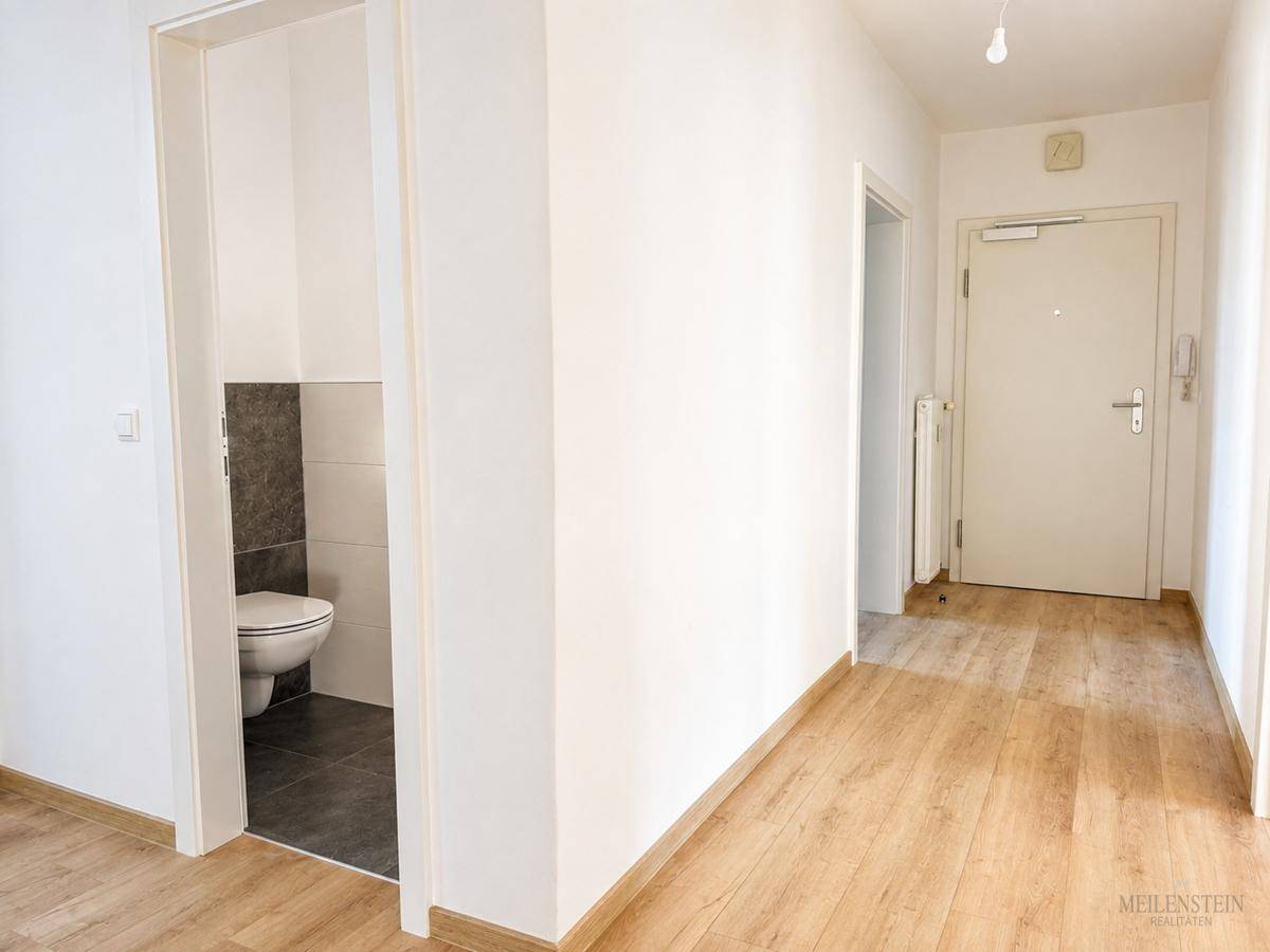Heller Flur mit Laminatboden und Zugang zu einem separaten Gäste-WC.