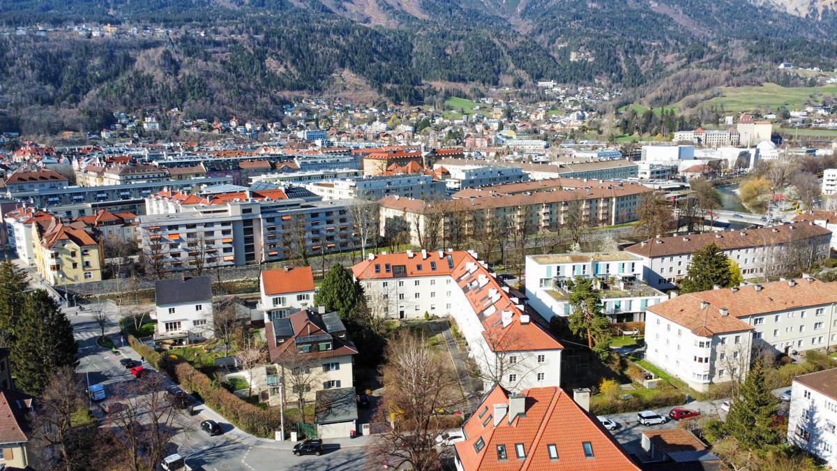 Panoramablick aus der Vogelperspektive auf eine Stadtlandschaft mit Bergen im Hintergrund.