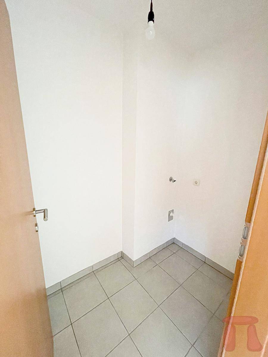 Kleiner Abstellraum mit Fliesenboden und Anschlüssen für eine Waschmaschine.