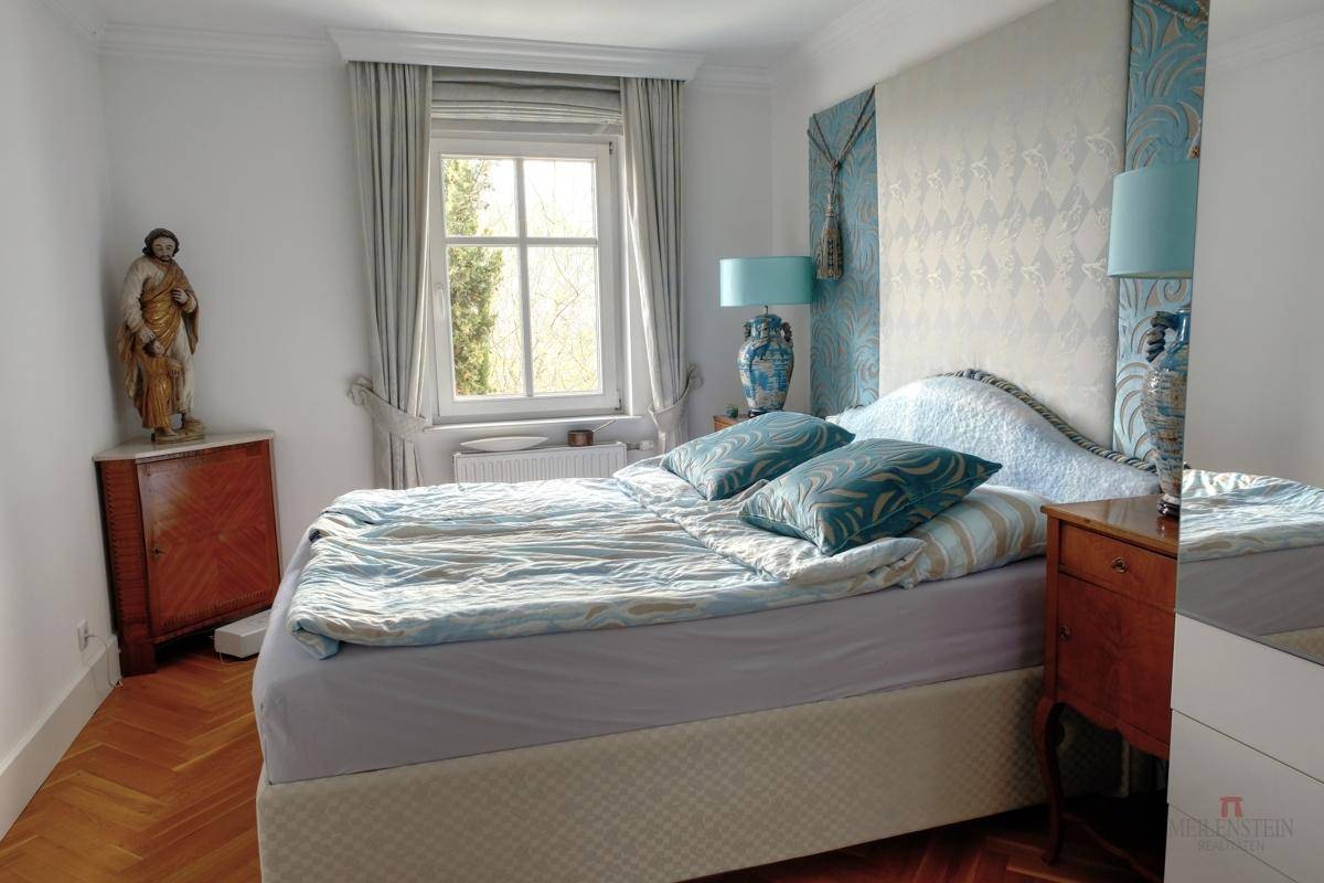 Gemütliches Schlafzimmer mit Parkettboden, großem Bett und Fensterblick.