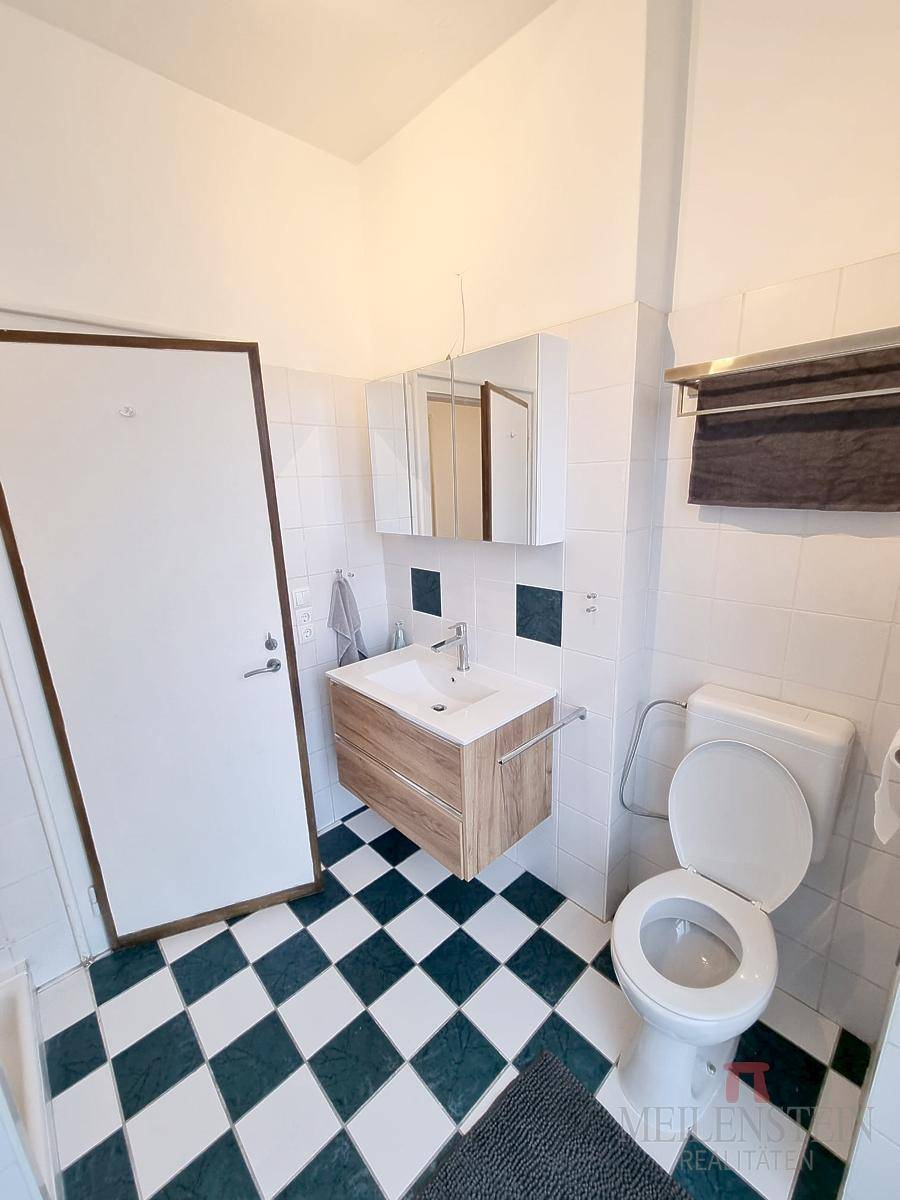 Badezimmer mit Schachbrettmuster-Fliesenboden, modernem Waschtisch und Toilette.