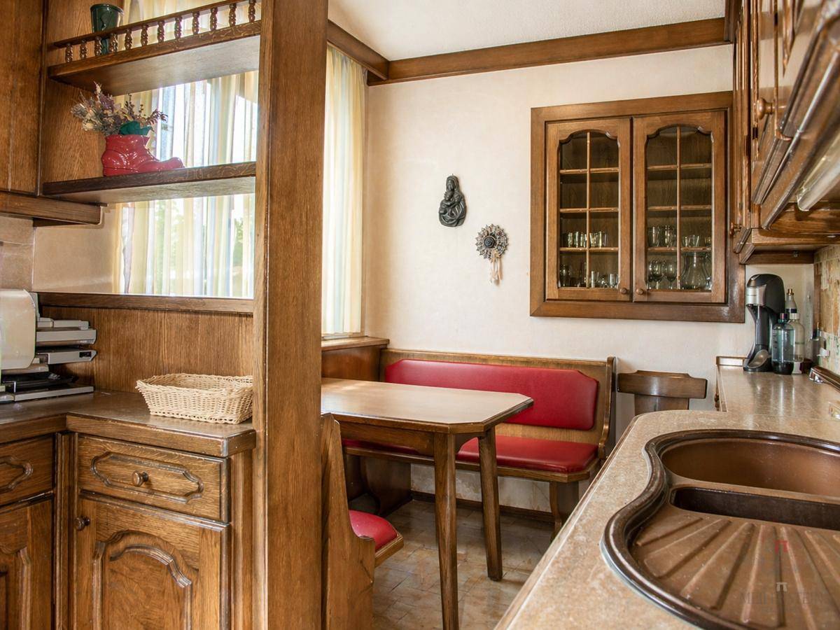 Traditionelle Küche mit Holzschränken, einer gemütlichen Essecke und einem Fenster für natürliches Licht.