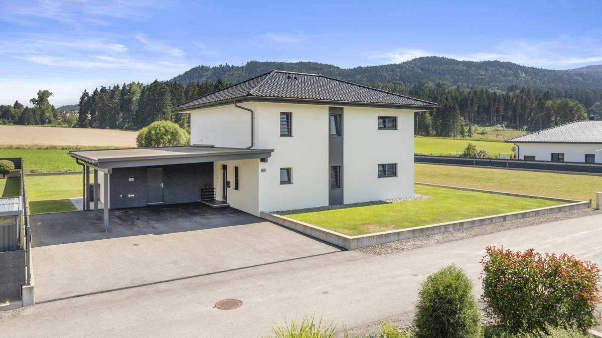 Vorderansicht des modernen Einfamilienhauses mit Carport und gepflasterter Auffahrt.