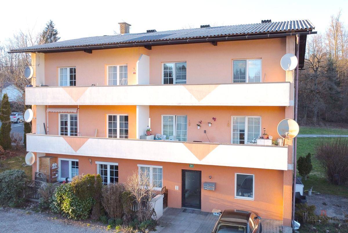 Mehrstöckiges Wohngebäude mit orangefarbener Fassade, Balkonen und Satellitenschüsseln.